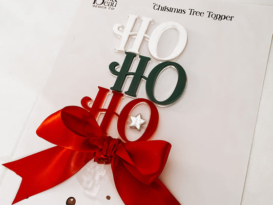 Handcrafted Acrylic Ho Ho Ho Tree Topper by Bell & Beau Design Co – a premium holiday decoration made from layered acrylic in Christmas colours, adorned with a luxurious red bow and silver star. Perfect for modern home Christmas décor or gift-giving.