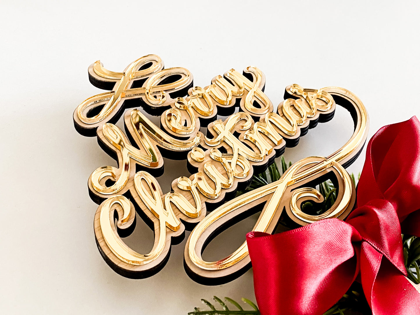 Rustic wooden and acrylic Merry Christmas Star Tree Topper with gold 3D lettering, featuring festive greenery and a red satin bow. This family tree topper makes a beautiful Christmas decoration and Christmas keepsake, perfect for a rustic Christmas or white star topper theme. A unique Xmas tree topper alternative designed to create lasting family memories and traditions year after year.