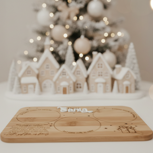 Wooden cutting board with engraved text in front of a Christmas village scene.