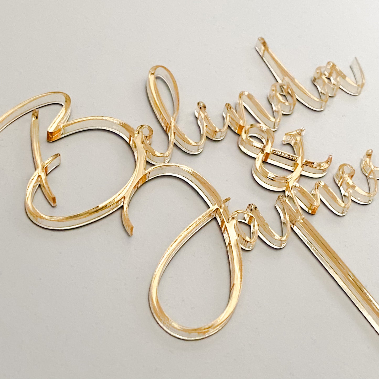 Custom gold wedding cake topper with names in a flowing modern script style, crafted from premium acrylic. Designed for brides and grooms who want a personalised finishing touch on their wedding cake. Ideal for weddings, anniversaries, and engagements. This custom cake topper is handmade in Australia, combining durability and elegance. A timeless keepsake to cherish, perfect for modern weddings with unique personalised décor.