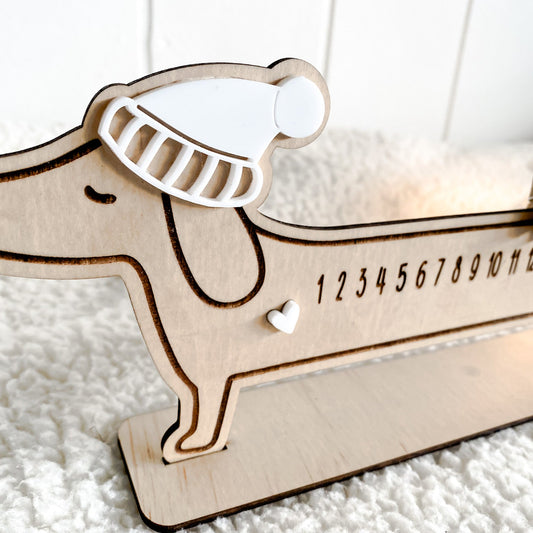 Close-up of the Sausage Dog Advent Calendar showing the laser-engraved numbers 1 through 24 and the small star mover