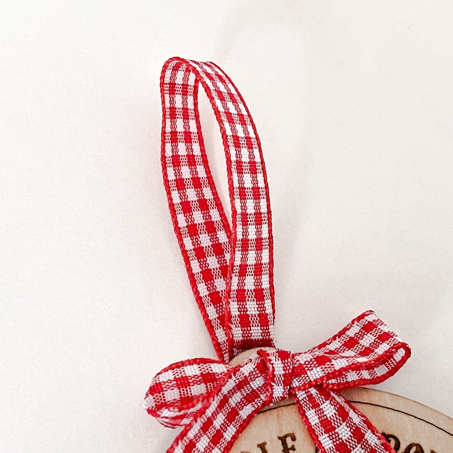 A close-up of the Nice & Naughty List Ornament Gingham ribbon, a wooden Christmas decoration