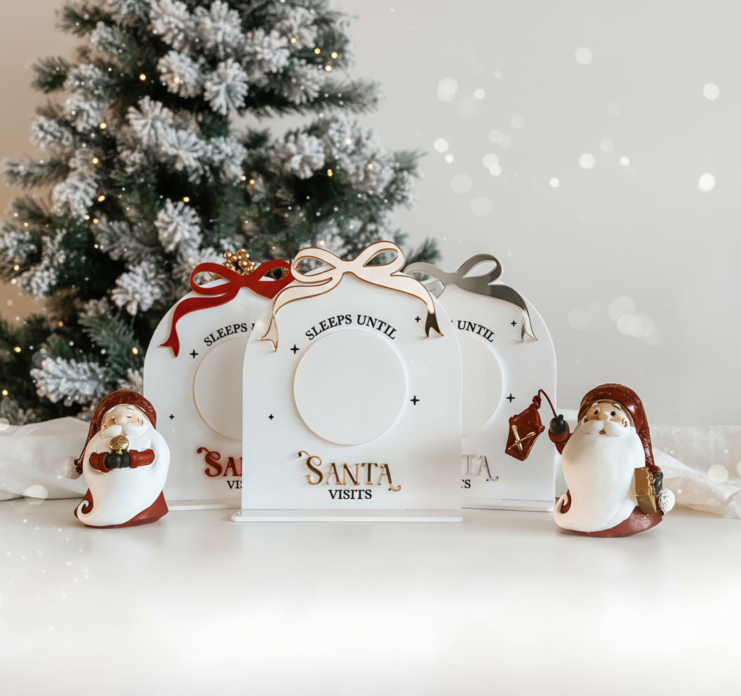 A group of Sleeps Til Santa Visits Signs in a range of colours surrounded by modern christmas decorations. Made in Australia by Bell & Beau Design Co.