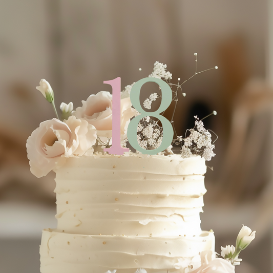 A professional product photo of a two-tier white buttercream cake decorated with peach roses and baby's breath, featuring a Modern Block Font "18" Cake Topper. The number 1 is in soft pink and the 8 is in sage green acrylic. This Minimalist Birthday Decor is perfect for Room Organisation themes or contemporary parties.