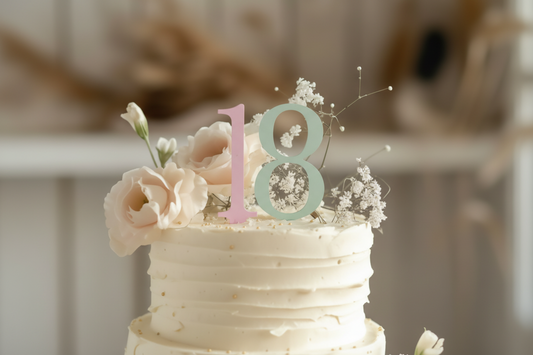 Modern Block Font acrylic numbers "18" used as a Single Digit Cake Topper combination on an elegant white ruffled cake. The pastel pink and green tones complement the Pretty Bedroom Decor aesthetic and rustic, soft-focus bakery background.