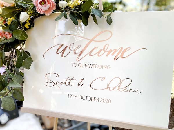 Contemporary Wedding Welcome Sign by Bell and Beau Design Co. The image displays a white acrylic sign background with Rose Gold lettering. Perfect for rustic or modern weddings.
