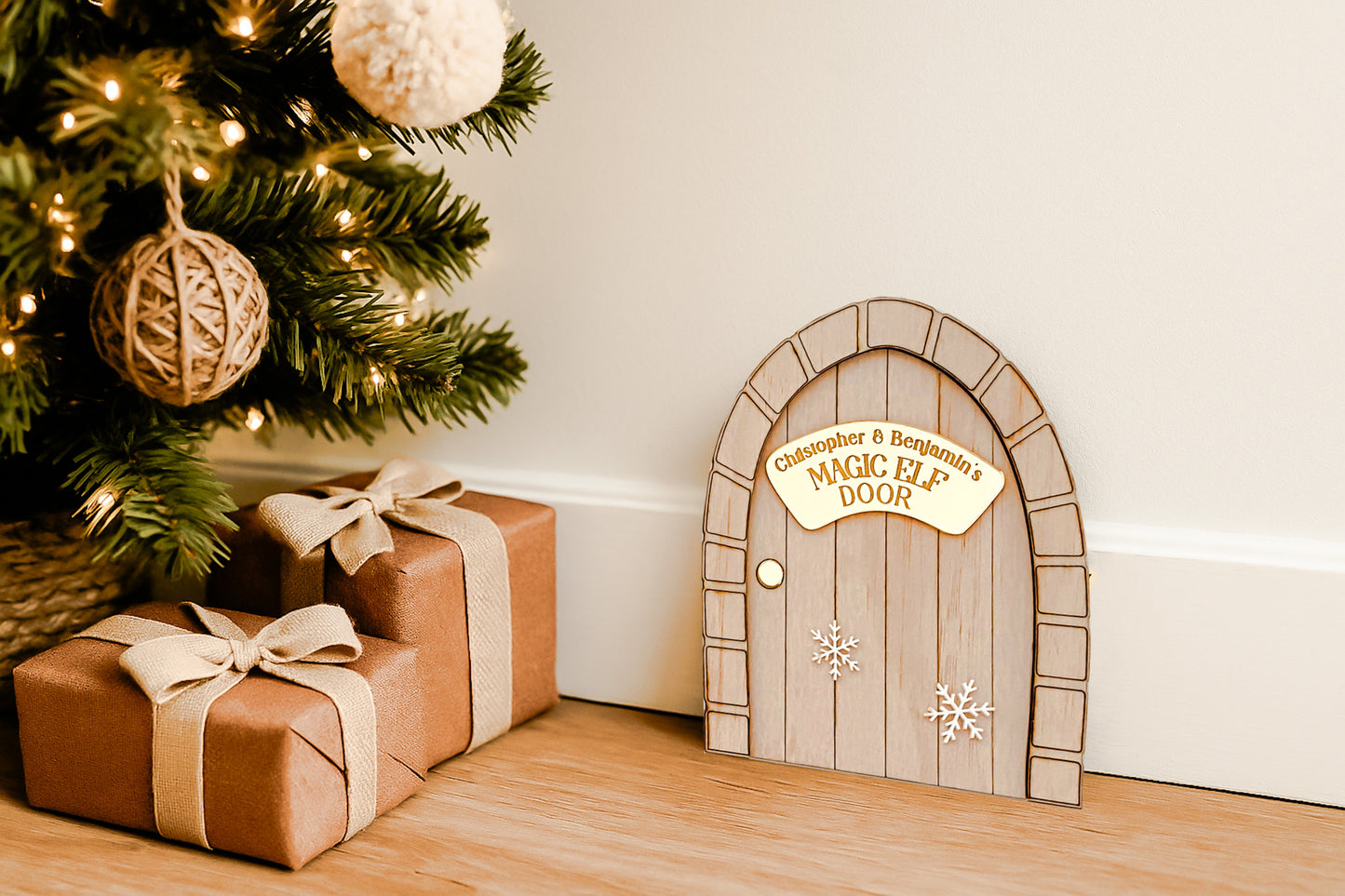 A handcrafted wooden Magic Elf Door with a brick-style arch, gold acrylic nameplate reading “ELF’S Magic Door,” and 3D white snowflake accents. A whimsical Christmas decoration for children to welcome their festive elf visitor. Personalised with children’s names, made from wood and acrylic, measuring 11 cm wide by 14 cm high.