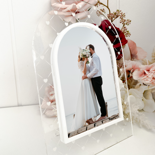 Decorative photo frame with a couple's photo inside, surrounded by flowers on a white background