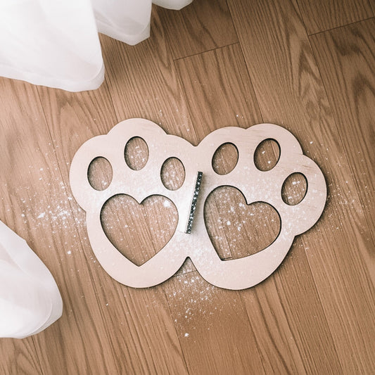 Wooden easter bunny paw-shaped foot stencil with heart cutouts on a wooden floor.