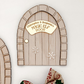 Christmas Elf Door with brick-style design, white snowflake details, and personalised name engraving option. A handcrafted wood and acrylic decoration that celebrates festive wonder and holiday charm.