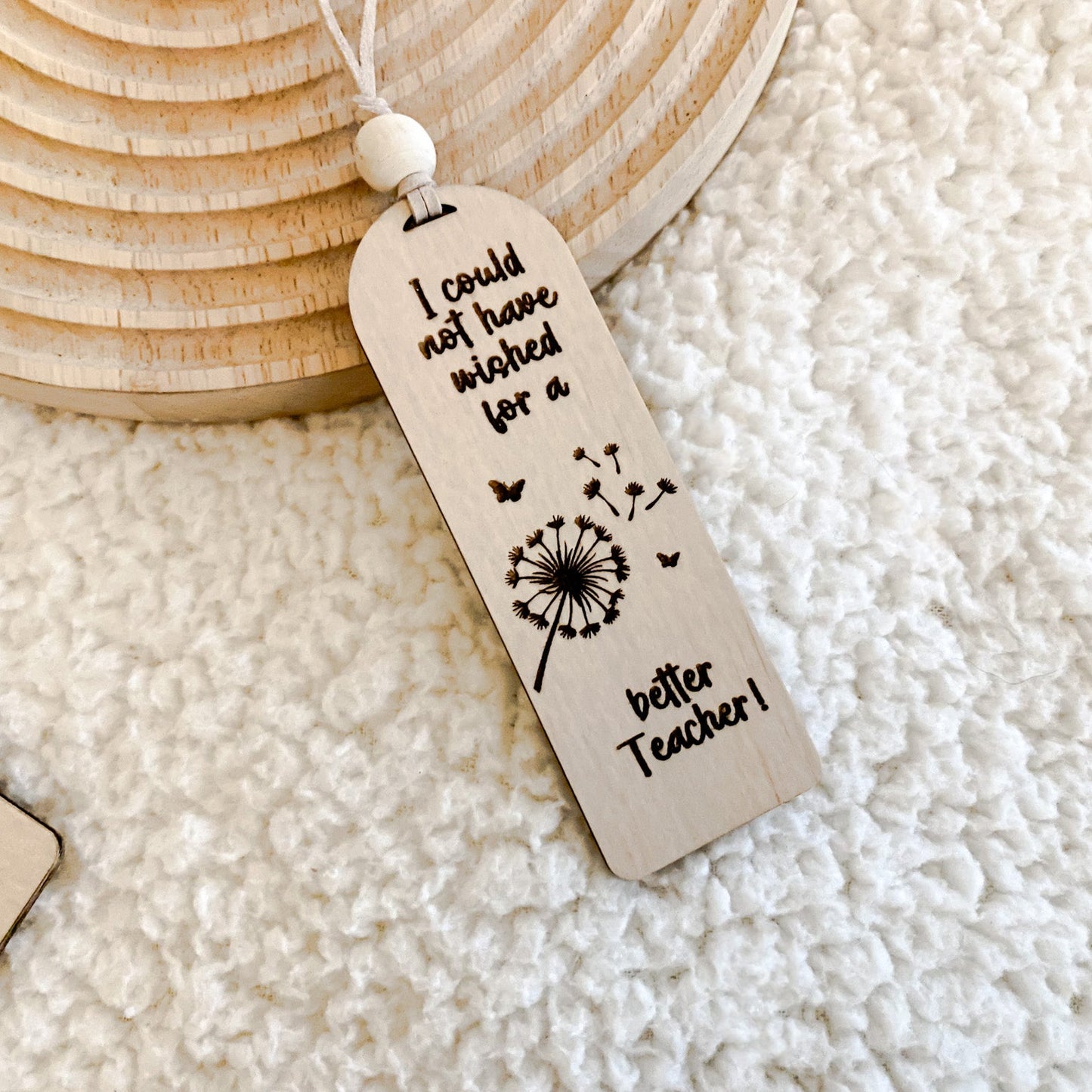 Teacher Appreciation Gift, Top-down view of an arch-shaped wooden bookmark engraved with a dandelion and teacher quote.