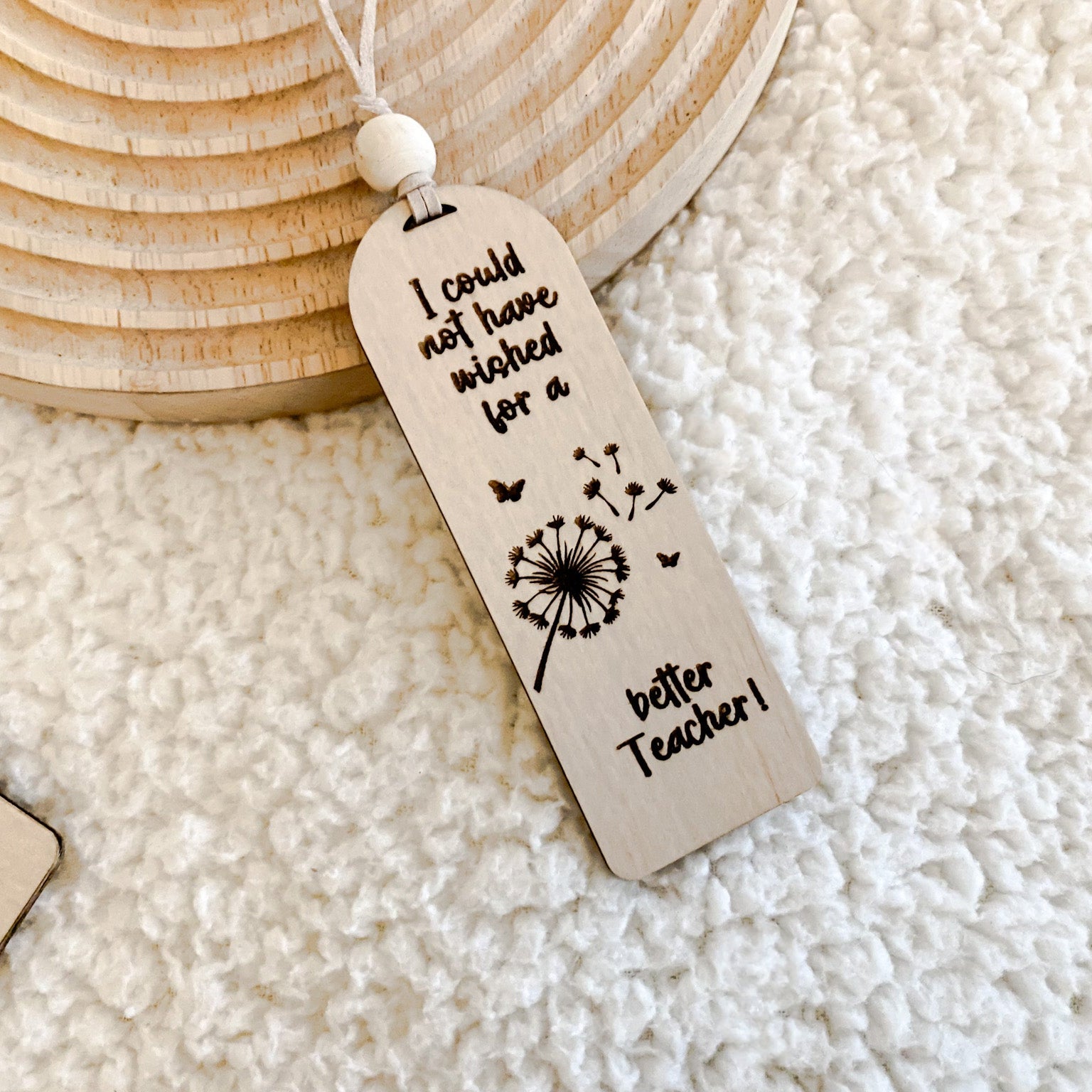 Teacher Appreciation Gift, Top-down view of an arch-shaped wooden bookmark engraved with a dandelion and teacher quote.