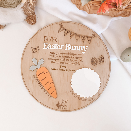 Easter Bunny Treat Tray Snack Board. Wooden plaque with Easter Bunny message on a white surface with decorative items.