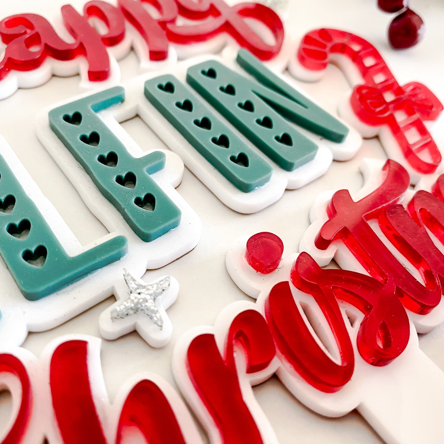 Unique acrylic Christmas tree topper reading ‘Happy Elfin Christmas’ with red and teal 3D lettering, red bow, and candy-cane accent — made in Australia.