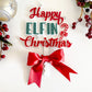 Happy Elfin Christmas tree topper with red ribbon — handcrafted acrylic Christmas décor by Bell & Beau Design Co., featuring layered lettering and festive candy-cane design on white background.