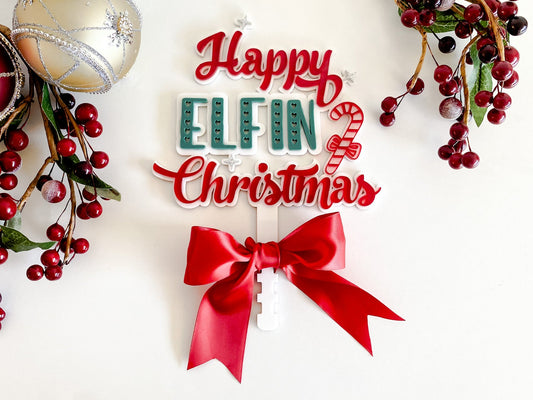 Happy Elfin Christmas tree topper with red ribbon — handcrafted acrylic Christmas décor by Bell & Beau Design Co., featuring layered lettering and festive candy-cane design on white background.