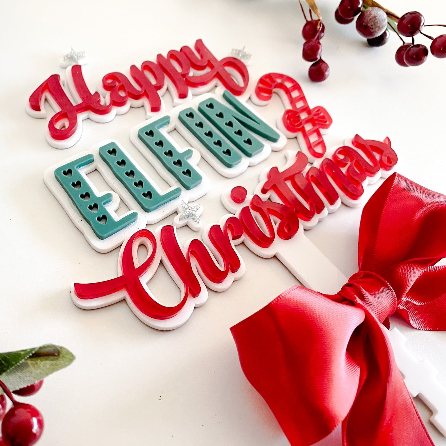 Modern Christmas tree topper in red, white, and green acrylic with rattan-inspired details and satin bow — Happy Elfin Christmas design.
