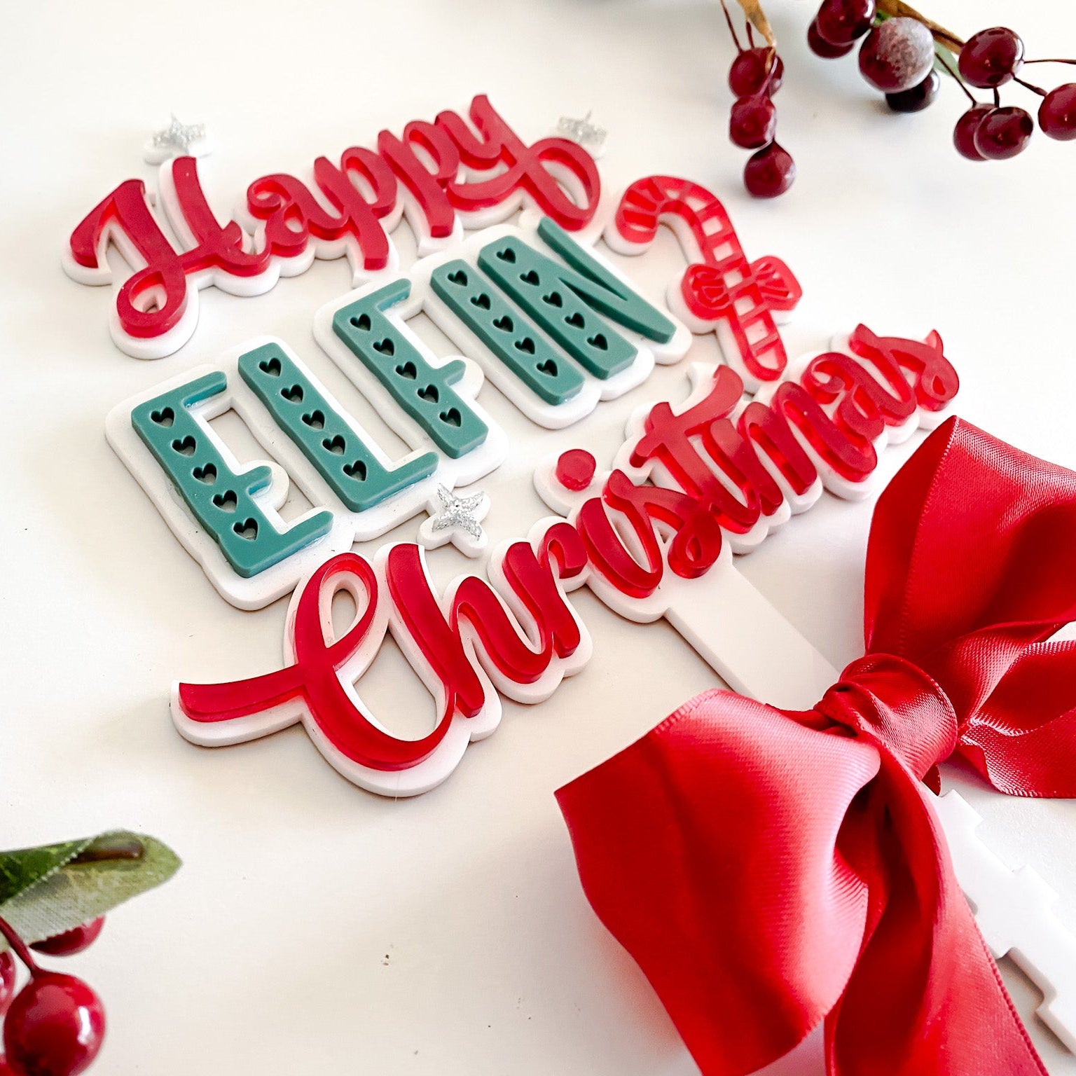 Modern Christmas tree topper in red, white, and green acrylic with rattan-inspired details and satin bow — Happy Elfin Christmas design.