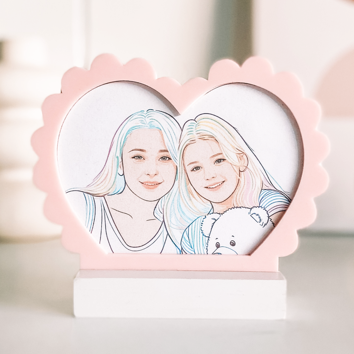 Heart-shaped frame with line art of two people holding a teddy bear, on a blurred background.