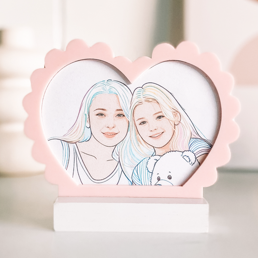 Heart-shaped frame with line art of two people holding a teddy bear, on a blurred background.