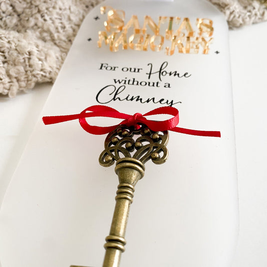 Frost White acrylic Santa’s Magic Key sign displayed on a festive neutral background. Includes gold text, vintage key with red ribbon, and white bow for hanging. Designed for families without chimneys, adding wonder and magic to Christmas Eve traditions.