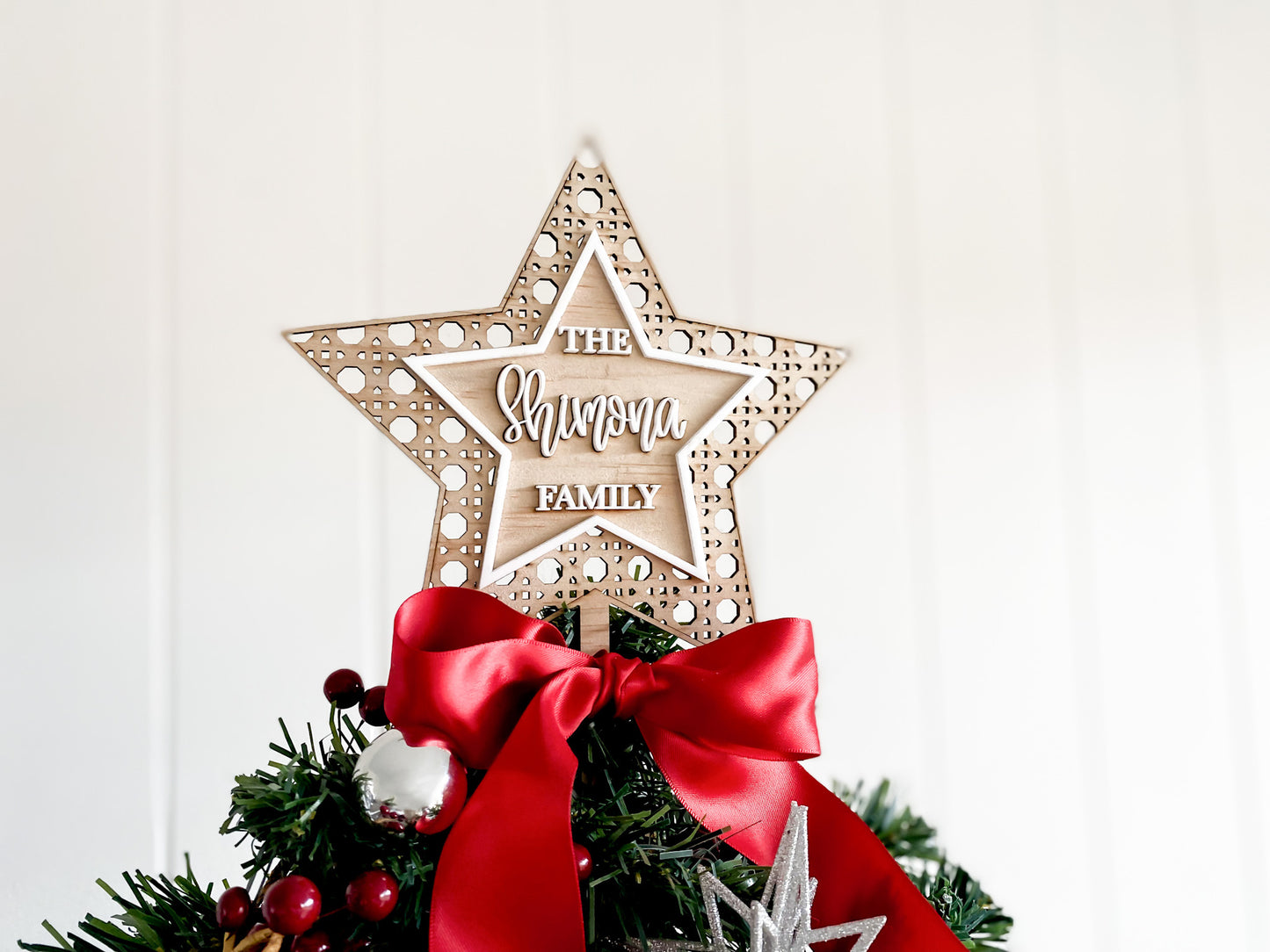 Rustic rattan star tree topper, engraved family name, eco friendly FSC plywood with red bow, sustainable handmade holiday décor.