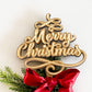 A handcrafted Merry Christmas Star Tree Topper made from layered wood and acrylic in gold lettering. This rustic Christmas tree decor features elegant 3D script text reading “Merry Christmas,” accented with festive greenery and a red satin ribbon. A timeless Christmas keepsake for family traditions and sustainable Christmas decorations, lovingly handmade in Australia by Bell & Beau Design Co.