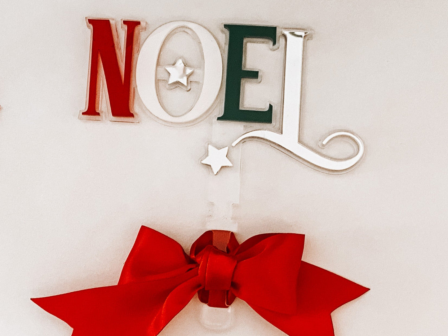 Handcrafted Noel tree topper featuring layered acrylic lettering in festive hues and a statement red ribbon. Designed by Bell & Beau Design Co to bring modern elegance to your Christmas décor. Lightweight, easy to attach, and made to last — a perfect keepsake for years of festive celebrations.