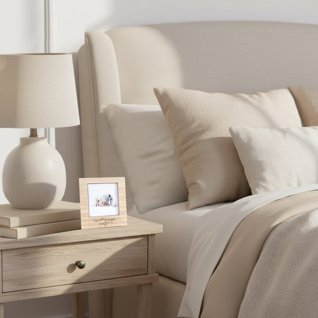 bedroom setting in neutral colours with a custom engraved wood frame beside the bed.