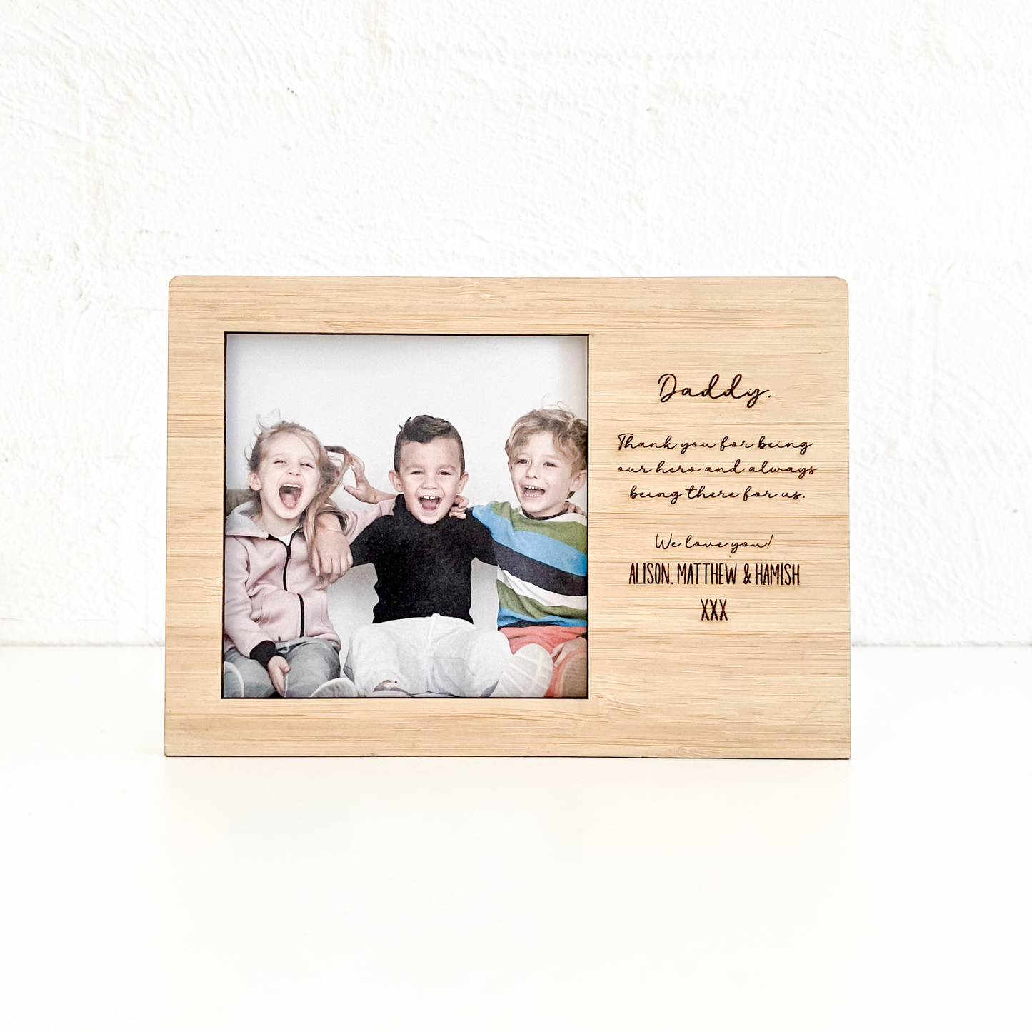 Wooden photo frame with a family photo and engraved message on a white background
