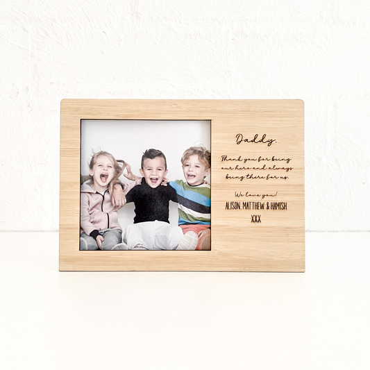 Wooden photo frame with a family photo and engraved message on a white background