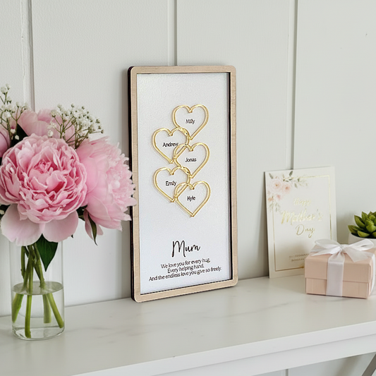Personalised Mother’s Day wooden plaque with custom 3D acrylic hearts on a white console table next to pink peonies and a gift.