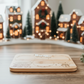 Dear Santa” engraved Christmas treat tray for cookies, milk, and carrots, made from sustainable bamboo wood. Styled in a cosy holiday setting with miniature gingerbread houses and twinkling Christmas lights.