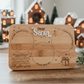 Wooden Santa treat tray engraved with “Dear Santa”, featuring designated circles for cookies, milk and reindeer treats. Handcrafted bamboo board on rustic wooden background with Christmas greenery — a sentimental Christmas Eve keepsake by Bell & Beau Design Co. Perfect for family traditions and festive photo styling.