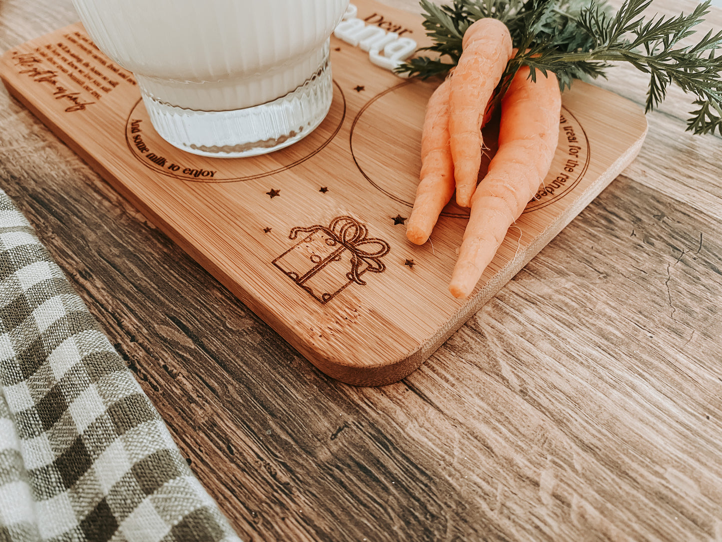 Christmas Eve treat board styled with milk glass, cookies, and carrot for the reindeer. Natural bamboo tray engraved with “Dear Santa”. Captures the excitement of children preparing for Santa’s visit — a heartfelt, reusable keepsake for family Christmas traditions.