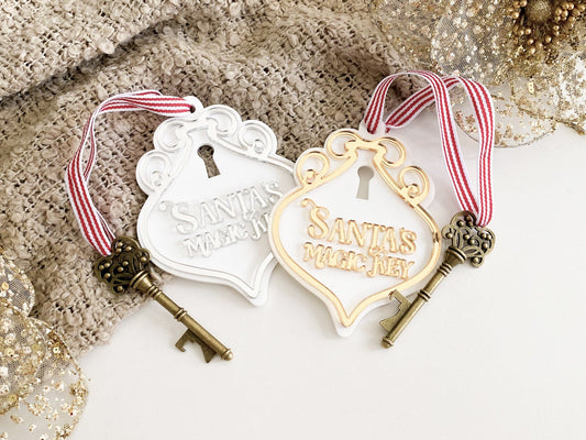 Two Santa’s Magic Key signs in gold and silver acrylic with vintage bottle-opener keys and red grosgrain ribbons, styled for Christmas Eve tradition.