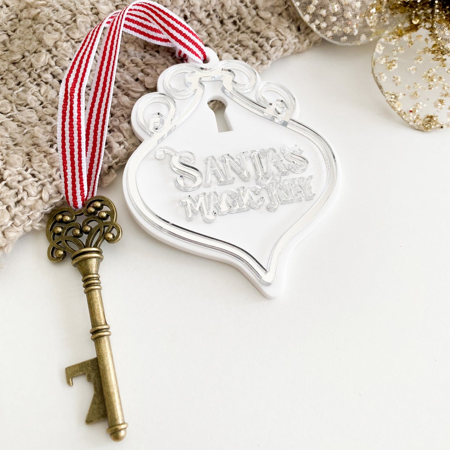 Silver acrylic Santa’s Magic Key ornament with antique brass key and grosgrain ribbon, ideal Christmas Eve keepsake for kids and families.