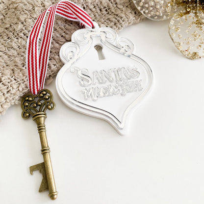 Silver acrylic Santa’s Magic Key ornament with antique brass key and grosgrain ribbon, ideal Christmas Eve keepsake for kids and families.