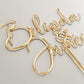 Custom gold wedding cake topper with names in a flowing modern script style, crafted from premium acrylic. Designed for brides and grooms who want a personalised finishing touch on their wedding cake. Ideal for weddings, anniversaries, and engagements. This custom cake topper is handmade in Australia, combining durability and elegance. A timeless keepsake to cherish, perfect for modern weddings with unique personalised décor.
