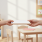 Child handing teacher a Customizable dry erase notes board on a white background, highlighting the blank writing area.
