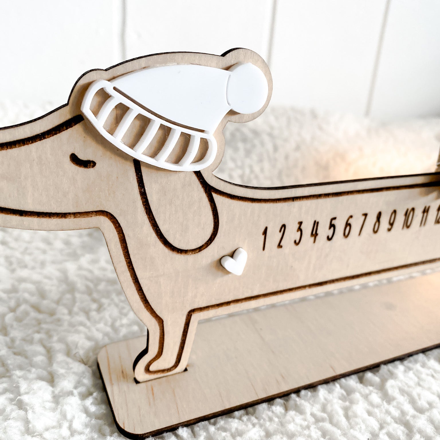 Close-up of the Sausage Dog Advent Calendar showing the laser-engraved numbers 1 through 24 and the small star mover