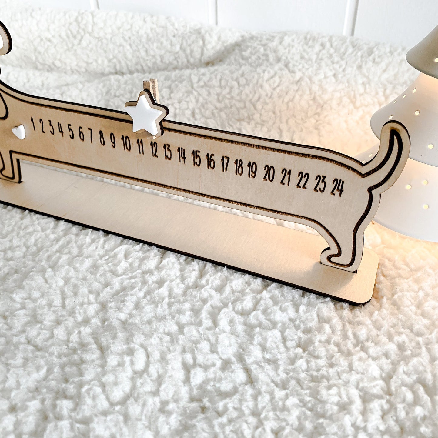 Funny dog Christmas decoration serving as a reusable countdown plaque on a textured white blanket.
