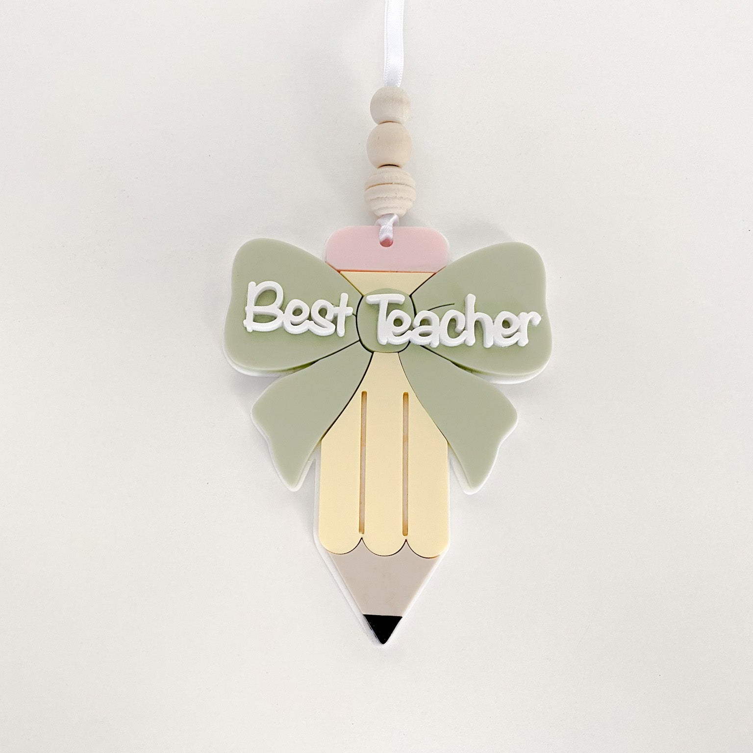 layered acrylic teacher appreciation ornament with a green bow and the words Best Teacher
