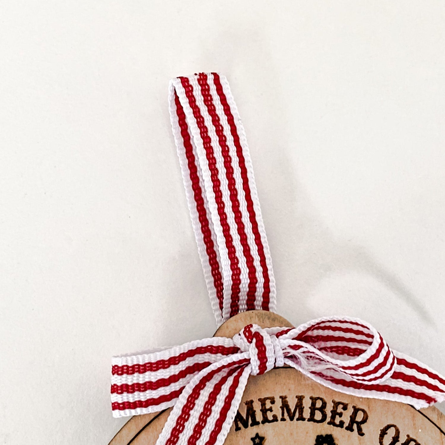 A close-up of the Nice & Naughty List Ornament stripe ribbon, a wooden Christmas decoration 
