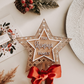 Rustic rattan star tree topper, engraved family name, eco friendly FSC plywood with red bow, sustainable handmade holiday décor.
