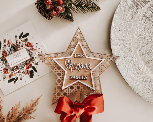 Rustic rattan star tree topper, engraved family name, eco friendly FSC plywood with red bow, sustainable handmade holiday décor.