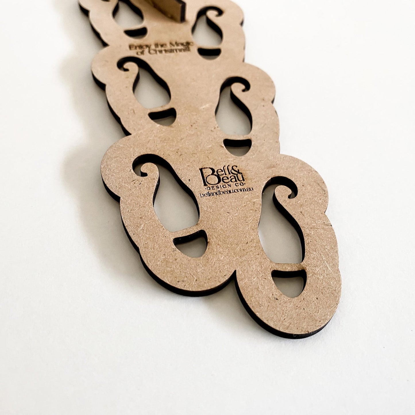 Close-up of the wooden Elf Footprint Stencil showing the interconnected design and the engraved lifting tab